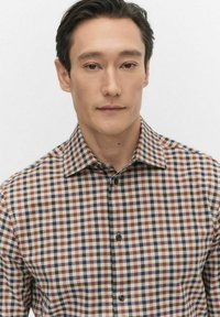 Rudetternet skjorte med en rig kombination af brune, marineblå og cremefarvede nuancer; struktureret krave og en subtil tekstur i stoffet.