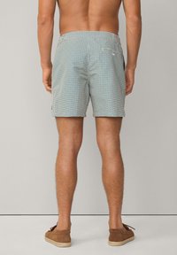Gemusterte Badeshorts in Türkis und Weiß mit elastischem Taillenbund und Gesäßtasche, kombiniert mit braunen Espadrilles.