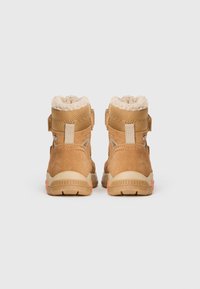 Brune ruskinds- og tekstilstøvler med en foring af shearling ved kraven, velcro-lukninger og en robust sål med orange accenter.