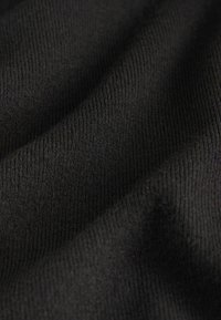 Gros plan sur la texture d'un tissu noir côtelé montrant de fines lignes verticales et des plis doux.