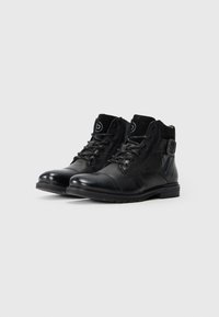 Botine negre din piele cu un finisaj neted, vârf rotund, sistem de închidere cu șireturi în față și detaliu cu cataramă pe lateral. Ușor texturat, cu cusături întărite.