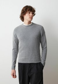 Maglione grigio lavorato a maglia con scollo rotondo e orlo a coste, realizzato in morbido materiale, caratterizzato da maniche lunghe e un design elegante.