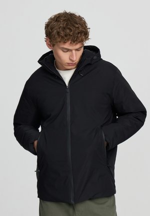 Giacca nera isolante con cappuccio, chiusura con zip e tasche laterali. Presenta una texture liscia e dettagli con cordoncino per una vestibilità regolabile.