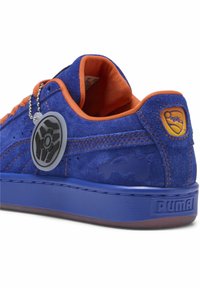 Sinine sametist spordijalanõud oranži tekstiilitäidisega, mis sisaldavad ümmargust logo silti ja Puma brändingut. Tekstuuriga kummitald ja tikandid.