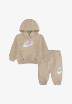 Beżowy zestaw dla malucha z bluzą z kapturem i spodniami, z wielokolorowym logo Nike i białym znakiem Swoosh na piersi oraz lewej nogawce spodni, z elastycznymi mankietami i pasem.
