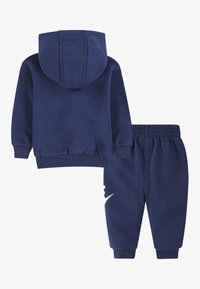 Set de hanorac cu glugă și pantaloni de trening de culoare albastru închis, realizat din bumbac, având glugă, manșete striate și detaliu cu logo alb pe pantaloni.