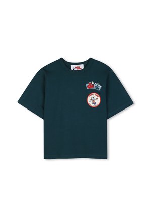 Camiseta de manga corta verde oscuro con pequeños parches rojos y azules en la parte superior izquierda del pecho, incluyendo un diseño circular de Mickey Mouse.