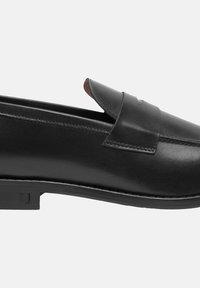 Mocassino in pelle nera con finitura liscia, punta tonda e dettagli cuciti. Presenta una fascia decorativa sullo scollo e un tacco modesto.