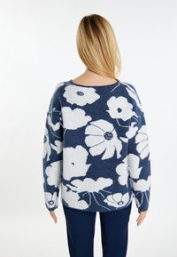Marineblauwe en witte gebreide sweater met bloemenpatroon in een ontspannen pasvorm, gekenmerkt door oversized bloemen en lange mouwen, gemaakt van een zachte, gestructureerde stof.