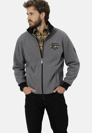 Graue Zip-Jacke aus dickem Stoff, mit schwarzem Kragen und Bündchen, bestickt mit Logodetails und einem Frontreißverschluss.