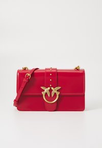 Červená kožená kabelka so zlatým vtáčikom, plochý dizajn, so študovanými detailmi a nastaviteľným popruhom. Hladká textúra a štruktúrovaný tvar.