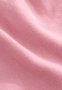 Tela rosa suave con textura fina y tejido tupido, y pliegues suaves que crean variaciones de luz y sombra.