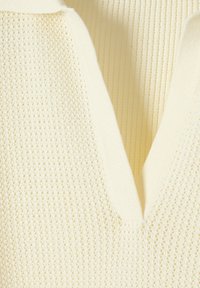 Maglione color crema a maglia con scollatura a V, bordi a costine e un motivo a rete aperta testurizzato.