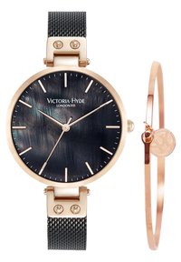 Montre avec bracelet en maille noire, boîtier rond en ton or, cadran texturé foncé et accents en or rose. Accompagnée d'un bracelet fin en or rose.