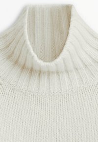 Un pull à col roulé de couleur crème en maille, présentant une texture côtelée et un col ajusté, fabriqué en fil doux avec une silhouette décontractée.
