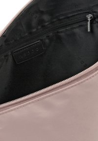 Ljusrosa zippered pouch gjord av slät tyg, med ett svart inrede som har en liten logotag och en dragkedja i metall.