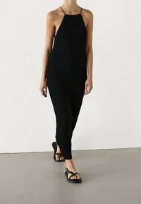 Mustat ribbed-maksimekot, joissa on ohuet hihnat, istuva siluetti ja sivureiät. Yhdistetty mustiin flip-flop sandaaleihin. Suuntaa-antava kangas.