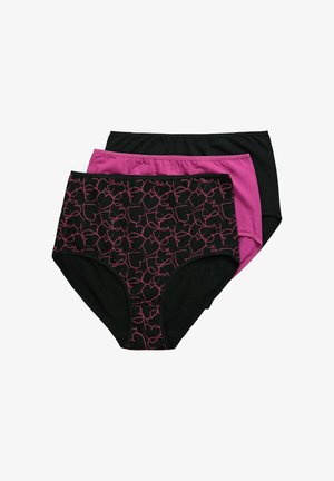 Donna con capelli biondi che indossa occhiali, reggiseno nero e mutandine nere a vita alta, posando davanti a uno sfondo chiaro e uniforme.