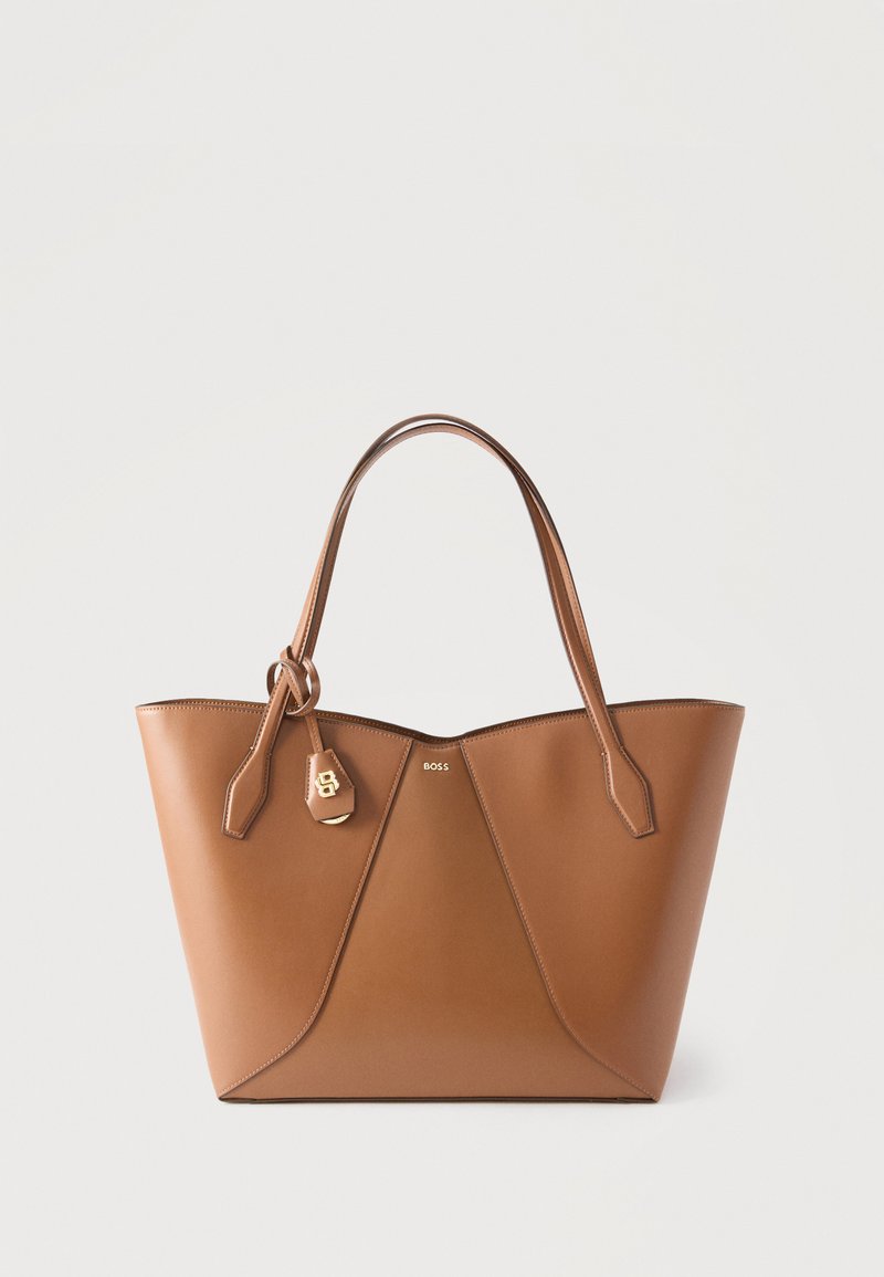 Καφέ τσάντα tote από δέρμα με διπλές λαβές, χρυσό λογότυπο "BOSS" και προσαρτημένη ετικέτα από δέρμα με χρυσά μεταλλικά εξαρτήματα σε λευκό φόντο.