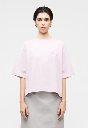 Hellrosa bauchfreies T-Shirt mit kurzen Ärmeln und erhabener Schriftprägung. Weiches Baumwollmaterial mit lockerem Schnitt.