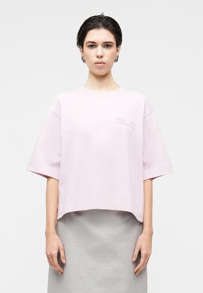 Ανοιχτό ροζ κοντομάνικο crop top με ανάγλυφη λεπτομέρεια κειμένου. Μαλακό βαμβακερό ύφασμα με χαλαρή εφαρμογή.