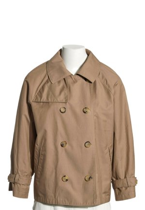 Trench-coat beige croisé avec grand col, poignets à boutons et deux poches avant, présenté sur un buste de mannequin blanc.