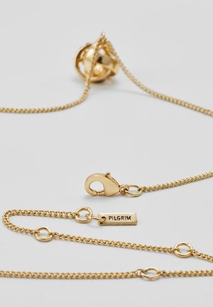 Goudkleurige ketting met een kreeftenhaaksluiting en een klein rechthoekig label gegraveerd met "PILGRIM" op een lichte achtergrond.