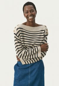 Pull rayé en beige clair et noir, présentant un design décolleté, des accents de boutons sur l'épaule et des poignets côtelés.