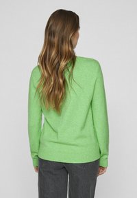 Zeleno pleteno pulover s okroglim dekoltejem, dolgimi rokavi, rebrastimi manšetami in robom. Gladka tekstura in sproščen kroj.