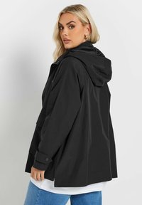 Svart huva jacka med avslappnad passform, med en framdragkedja, två sidofickor och knäppte ärmavslut. Slät tyg och minimal design.