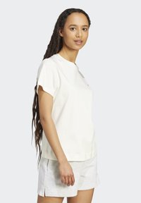 Weißes T-Shirt mit kurzen Ärmeln aus weichem Stoff und leicht lockerer Passform, mit rundem Ausschnitt und minimalistischen Details.