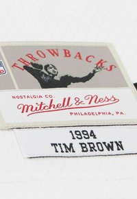Throwbacks-Patch mit einer feiernden Sportler-Illustration, Mitchell & Ness-Logo, Philadelphia PA und einem Namensschild "1994 Tim Brown" auf weißem Stoff.