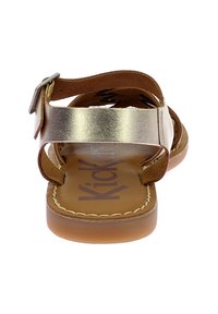 Sandalias con correa metálica dorada y detalles en cuero marrón, con hebilla ajustable y plantilla acolchada. Suela plana con detalle de costura visible.