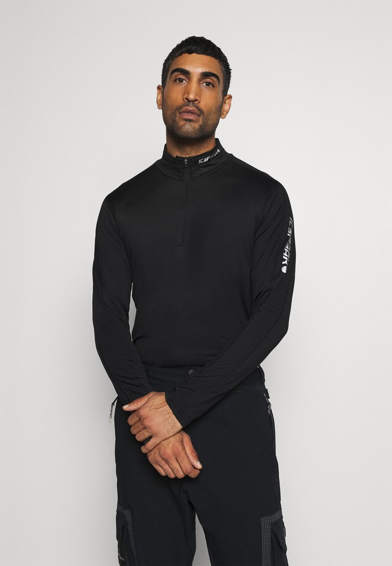 Haut noir à manches longues avec un col zippé à mi-hauteur. Présente une texture lisse et des accents de marque sur le col et la manche.
