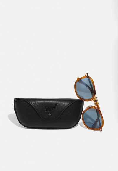 Les lunettes de soleil Persol présentent une monture en écaille de tortue orange, des verres bleus, et sont livrées avec un étui en cuir noir embossé avec "Persol."