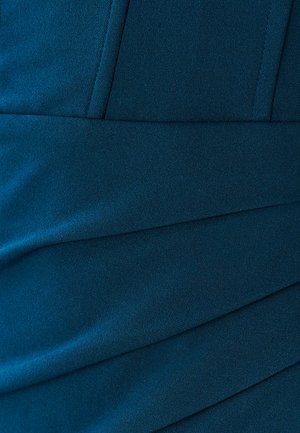 Teal stof med en glat tekstur, der har diagonale pleats og syninger for struktur.