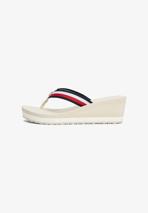 Sandalias de cuña beige con una suela blanca. Presentan una tira entre los dedos en azul marino y dos rayas horizontales en rojo y blanco. Suela texturizada para un mejor agarre.