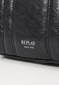 Borsa in pelle nera con finitura testurizzata e pannellatura verticale. Mostra la scritta "REPLAY" e "SINCE 1981" in caratteri metallici argento.
