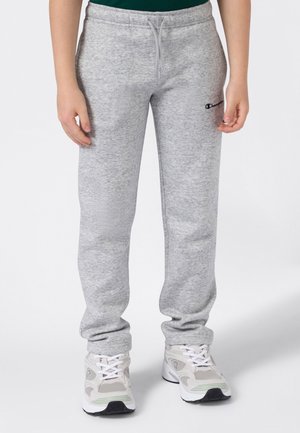 Graue Jogginghosen mit einem Kordelzugbund, ausgestattet mit einem strukturierten Stoff, geradem Bein-Design und einem kleinen Logo auf der Hüfte. Getragen mit weißen Sportschuhen.