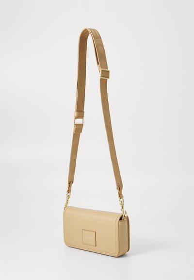 Beige leather crossbody bag with adjustable woven strap and gold-tone hardware, rectangular shape, and stitched logo patch on front.