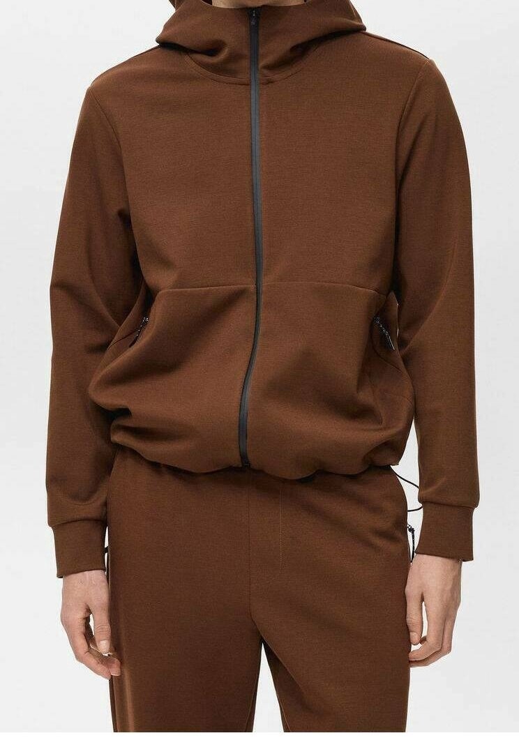Felpa brown con zip realizzata in tessuto morbido, dotata di cappuccio, due tasche frontali e dettagli neri sulla zip. Vestibilità comoda con polsini a costine.