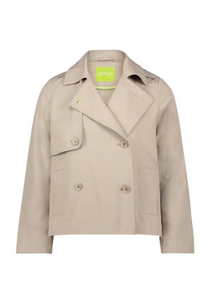 Giacca beige doppiopetto con colletto a punta, tasche laterali e etichetta verde. Realizzata in tessuto liscio con una forma leggermente strutturata.