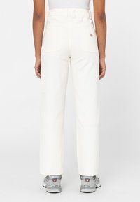 Vita cargo-byxor med hög midja, två bakfickor och sidofickor, matchade med grå sneakers. Mjuk bomullstyg, rak benmodell.