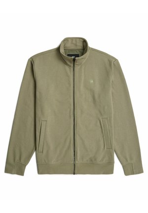 Chaqueta con cremallera de color verde olivo, hecha de material suave, con cuello alto, dos bolsillos laterales y un logo minimalista en el lado izquierdo del pecho.