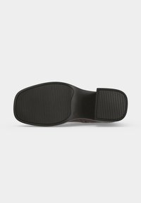 Semelle d'une chaussure noire habillée avec un bout carré arrondi et un grip en caoutchouc texturé au niveau du talon et de l'avant-pied.