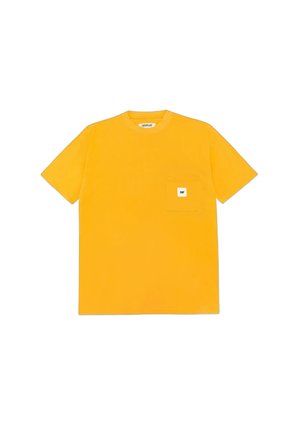 Camiseta amarilla de manga corta con un pequeño bolsillo en el pecho que presenta una etiqueta blanca cuadrada con el texto "CAT".