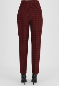 Rood en zwart houndstooth-patroon broek, op maat gemaakt, met een zachte textuur, hoge taille en taps toelopende pijpen. Draagt het met zwarte hakken.