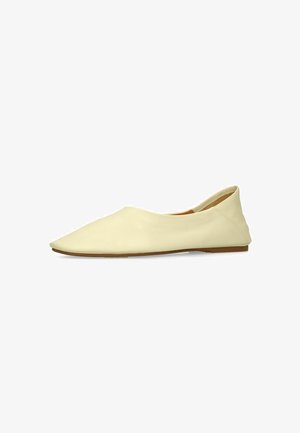 Crèmekleurige platte schoen met een puntige neus, een lage achterkant en een glad leren bovenwerk op een witte achtergrond.