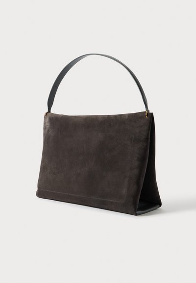 Tumši brūna taisnstūrveida zamša rokassoma ar vienu platu melnas ādas siksnu un zelta toņa metāla detaļām uz balta fona.