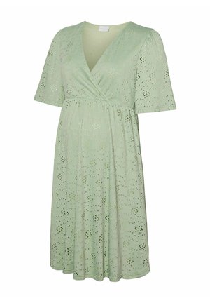 Robe vert clair arrivant au genou avec manches courtes, corsage croisé en V, et motif floral ajouré sur toute la surface.